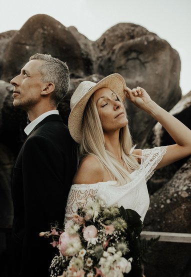 Brudepar med ryggen til hinanden foran klipper i Nordic Park